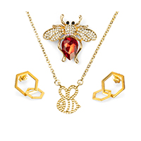 Eine goldene Kette mit Wabenanhänger, zwei passende goldfarbene Waben-Ohrstecker und eine rot-goldene Brosche zentriert angeordnet