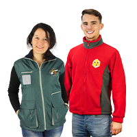 A woman is wearing a dark green beekeeper's waistcoat and a man is wearing a red fleece jacket