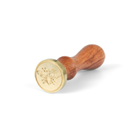 eine Rolle GeschenkpapierEin Wachssiegel-Stempel liegend mit Bienenmotiv zum Betrachter mit Bienenmotiv leicht auseinandergerollt