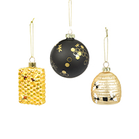 Three Christmas baubles, one black with a golden honeycomb pattern, one in the shape of a beehive and one in the shape of a honeycomb, arranged slightly offset in the centre.