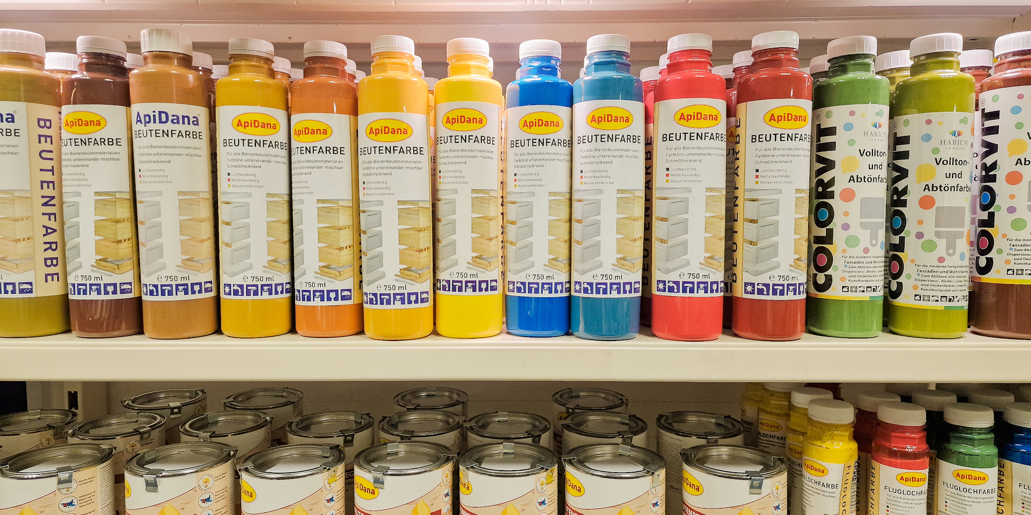 Beutenanstriche stehen hell beleuchtet und nach Farben sortiert im Regal
